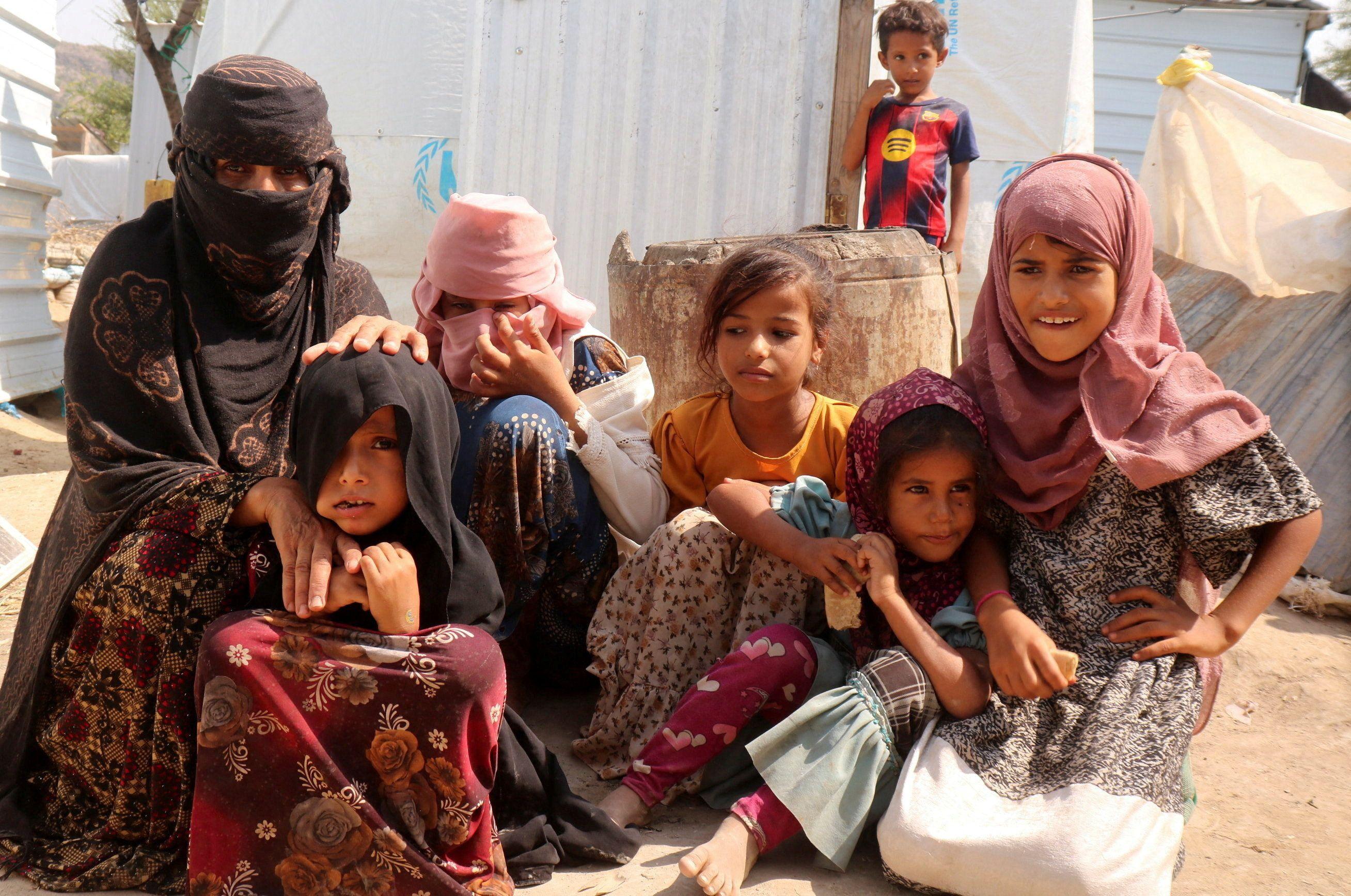 A displaced family carrying water near temporary shelters in Taiz governorate.